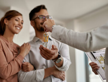 Close-up of real estate agent giving new house keys to a couple.